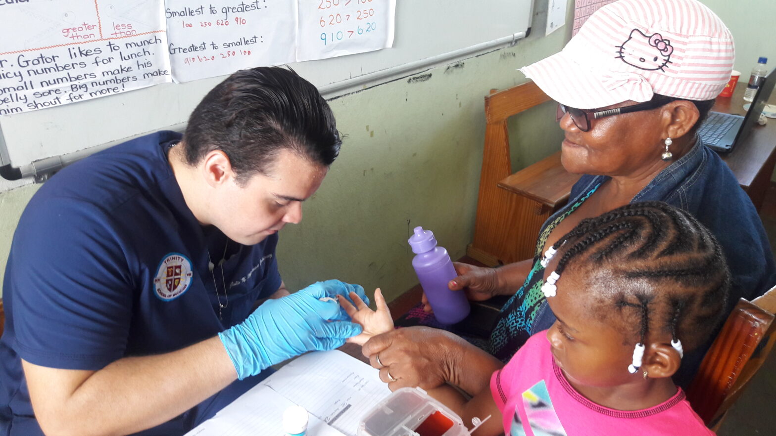 Trinity medical school student assisting a local family