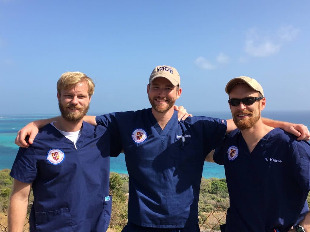 Three Caribbean medical school students smiling in front of the ocean