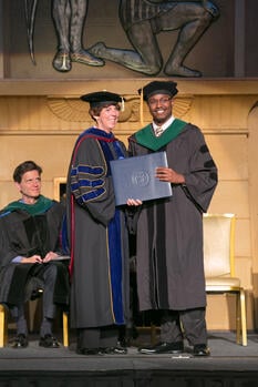 Gamal Fitzpatrick recieving diploma on stage at graduation