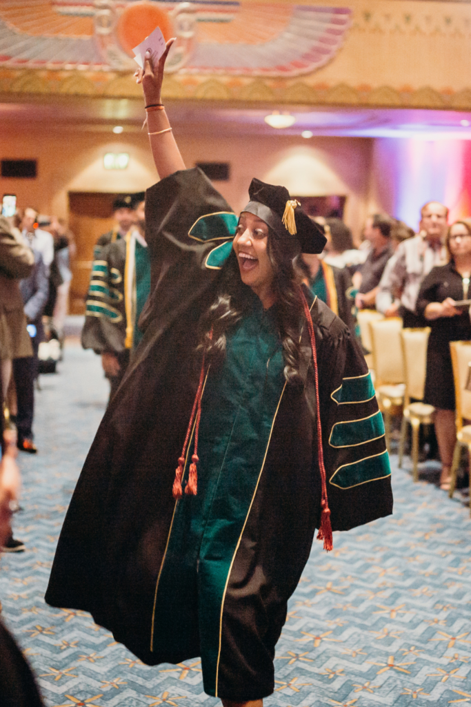 Student waving at graduation representing medical school tuition and frees